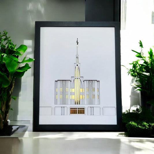 A framed art print featuring a minimalist architectural illustration of a temple, styled on a windowsill with green plants on either side.
