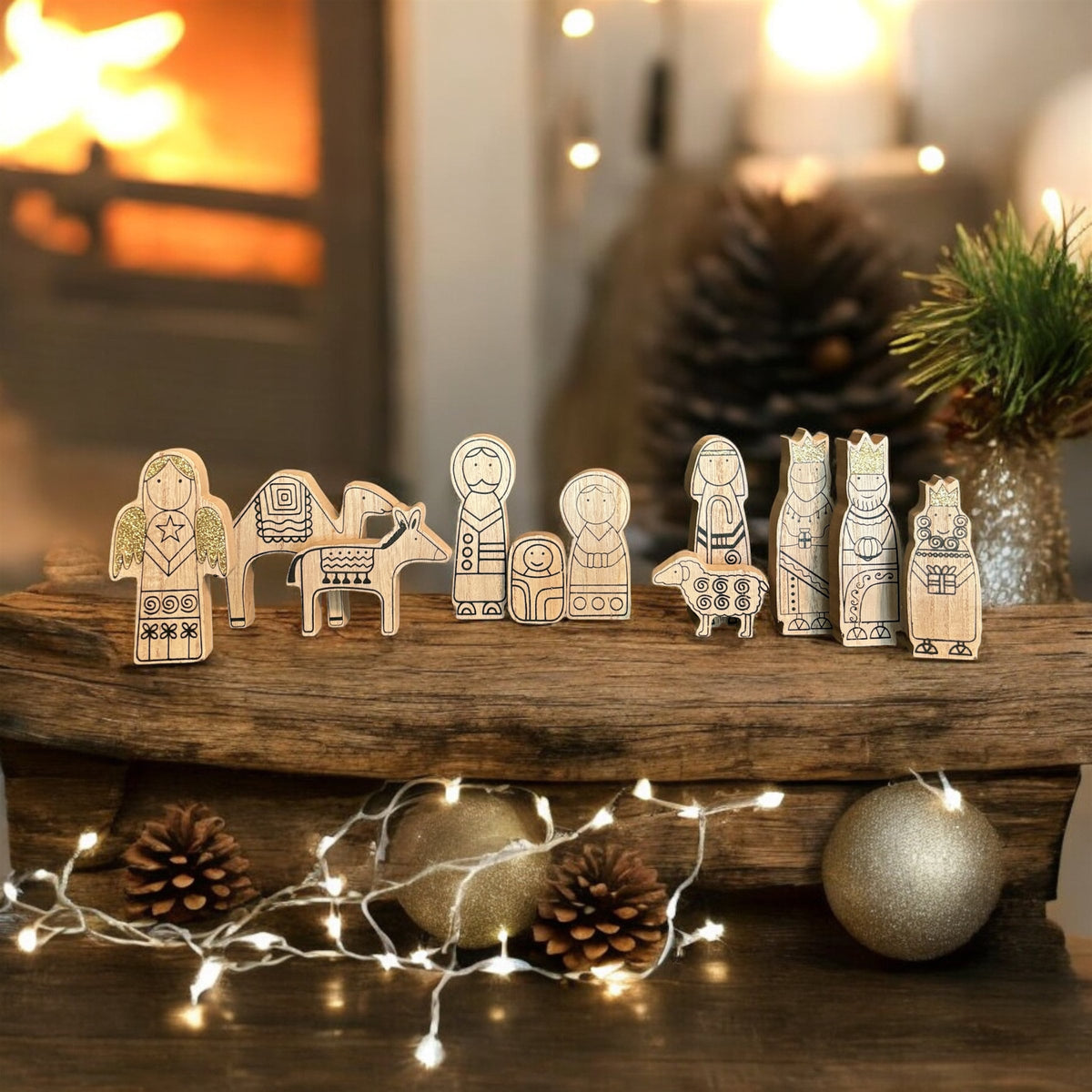 A set of small wooden nativity figures with engraved patterns, arranged on a rustic wooden shelf in a cozy holiday setting with warm lights, pinecones, and ornaments.