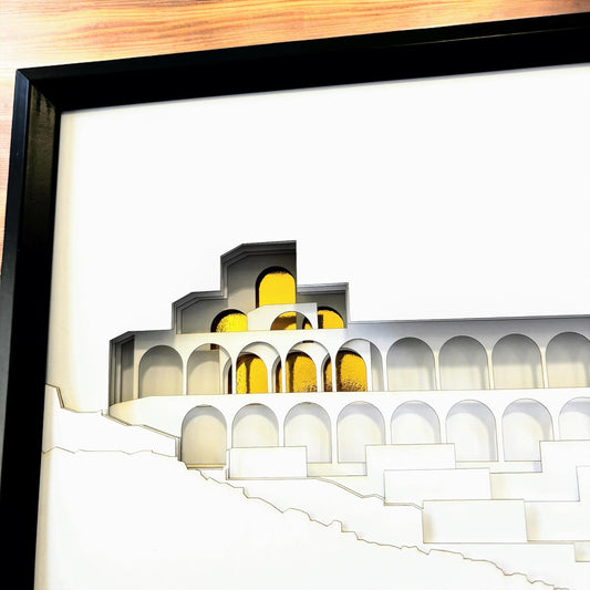 A framed architectural art print featuring a white geometric structure with yellow arched windows, set in a black frame against a white mat.