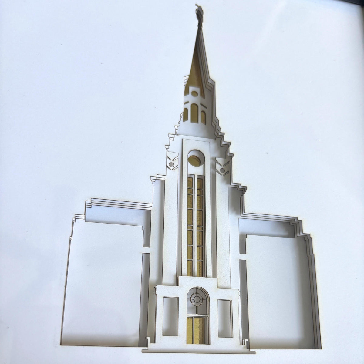 A cutout architectural model of a temple spire, likely a LDS Church temple replica, shown against a plain white background.