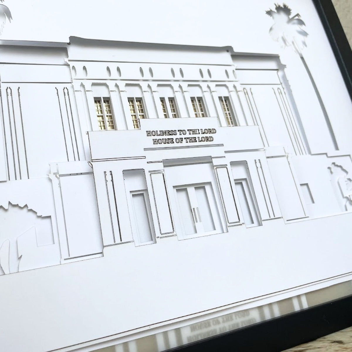 A framed white laser-cut architectural art print depicting the Hollywood Signpost Building, featuring a black frame and a textured beige background visible on the right. Mesa Temple Art Shadow Box