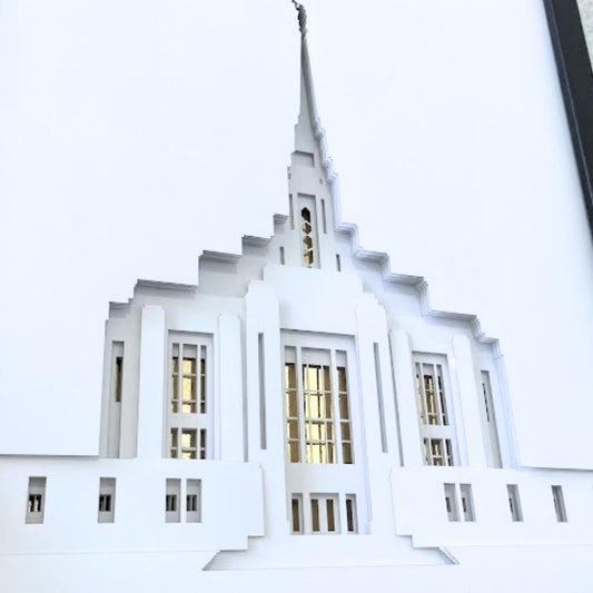 A white 3D papercut sculpture of the Seattle Temple, framed in black and displayed against a light textured wall. Ogden Temple Art Shadow Box