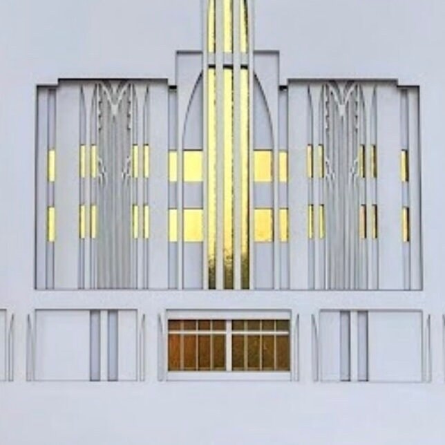 A modernist-style architectural facade design or model featuring symmetrical white and gray geometric forms with prominent gold vertical window panels and a central arched section.