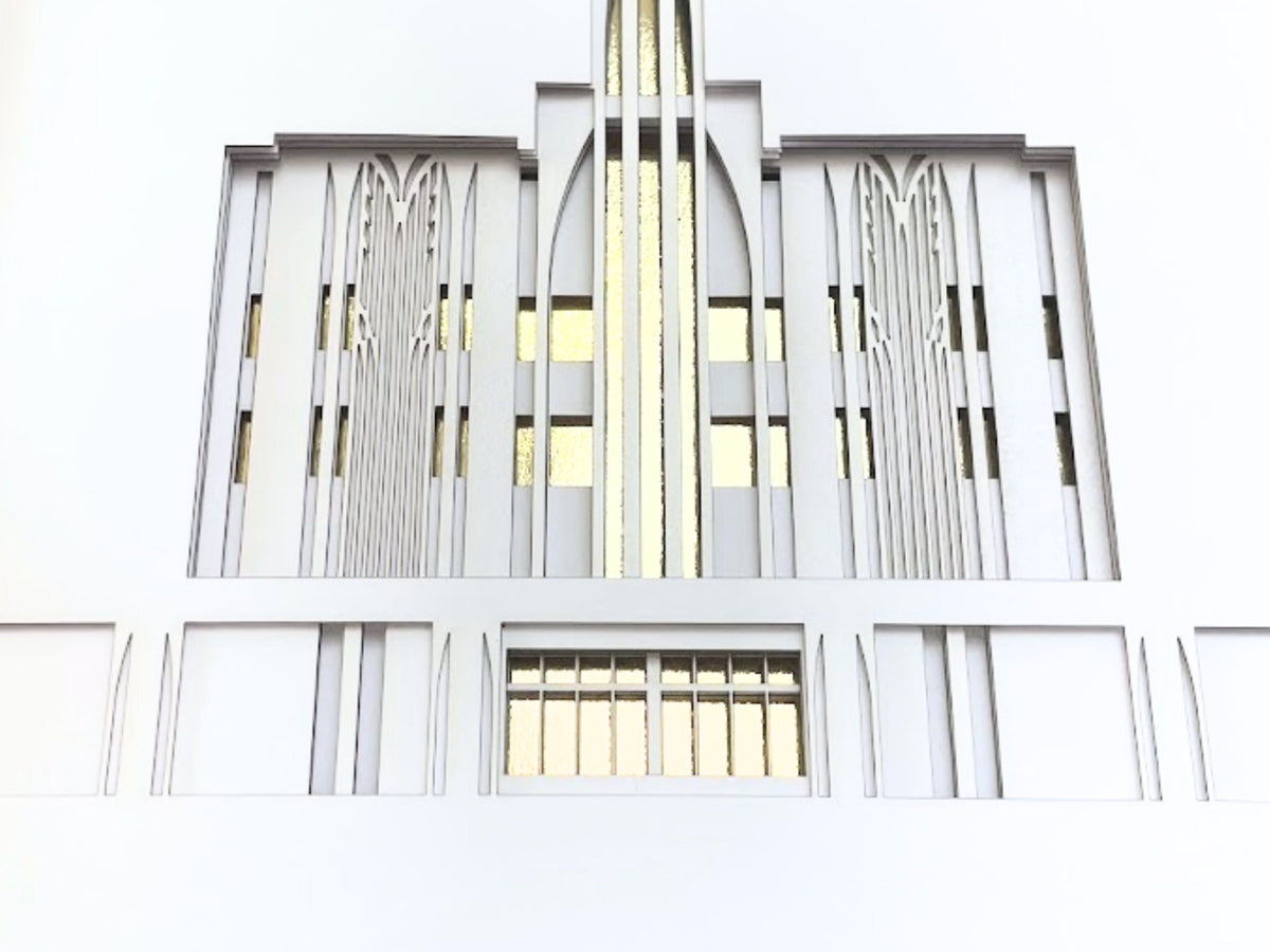 A close-up of a white architectural facade or decorative wall panel with vertical lines, arched window-like sections, and a central gold-toned vertical accent.